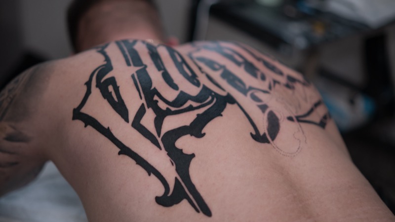 Großes Blackletter-Lettering auf dem Rücken während der Arbeit – rechts ist die Vorzeichnung für den nächsten Teil sichtbar