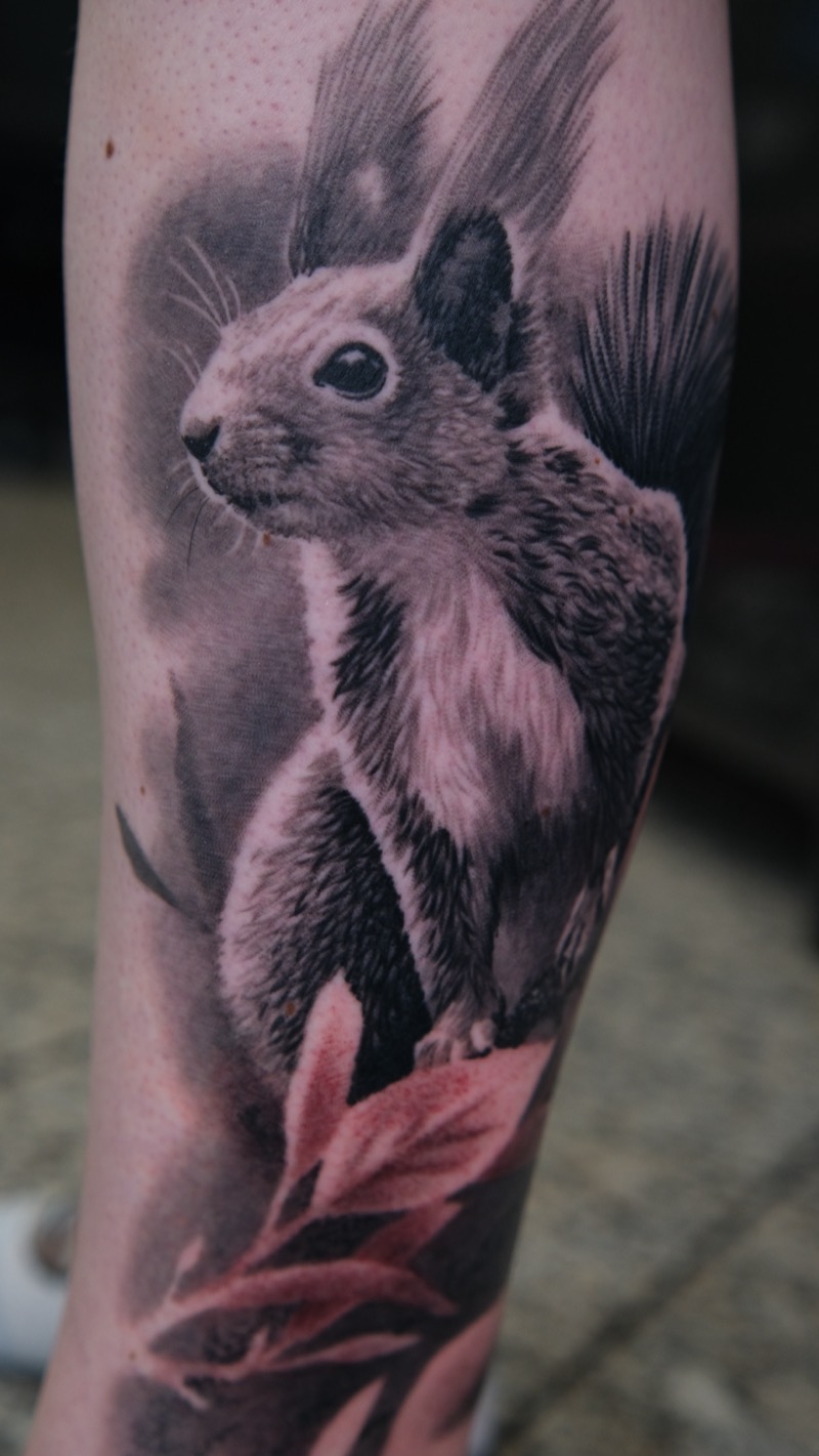 Tier-Tattoo am Unterschenkel: realistisches Eichhörnchen mit feiner Fellstruktur, Blätter mit dezentem Rotton